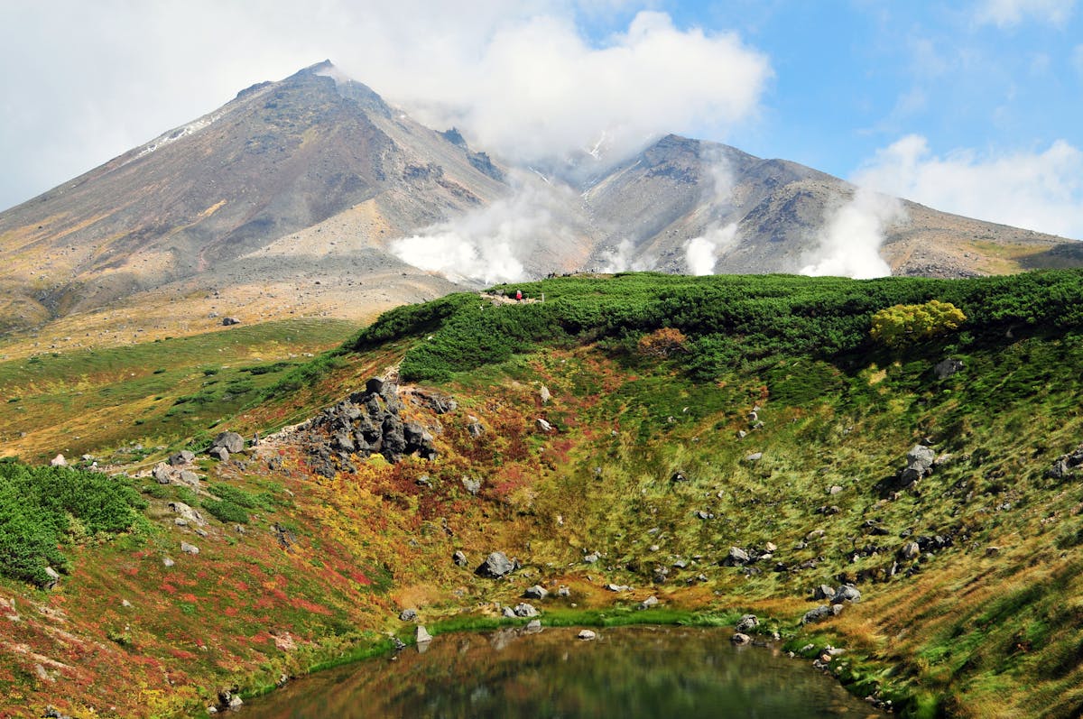 Steaming geothermal vents surrounded by autumn foliage at Mount Asahi Hokkaido