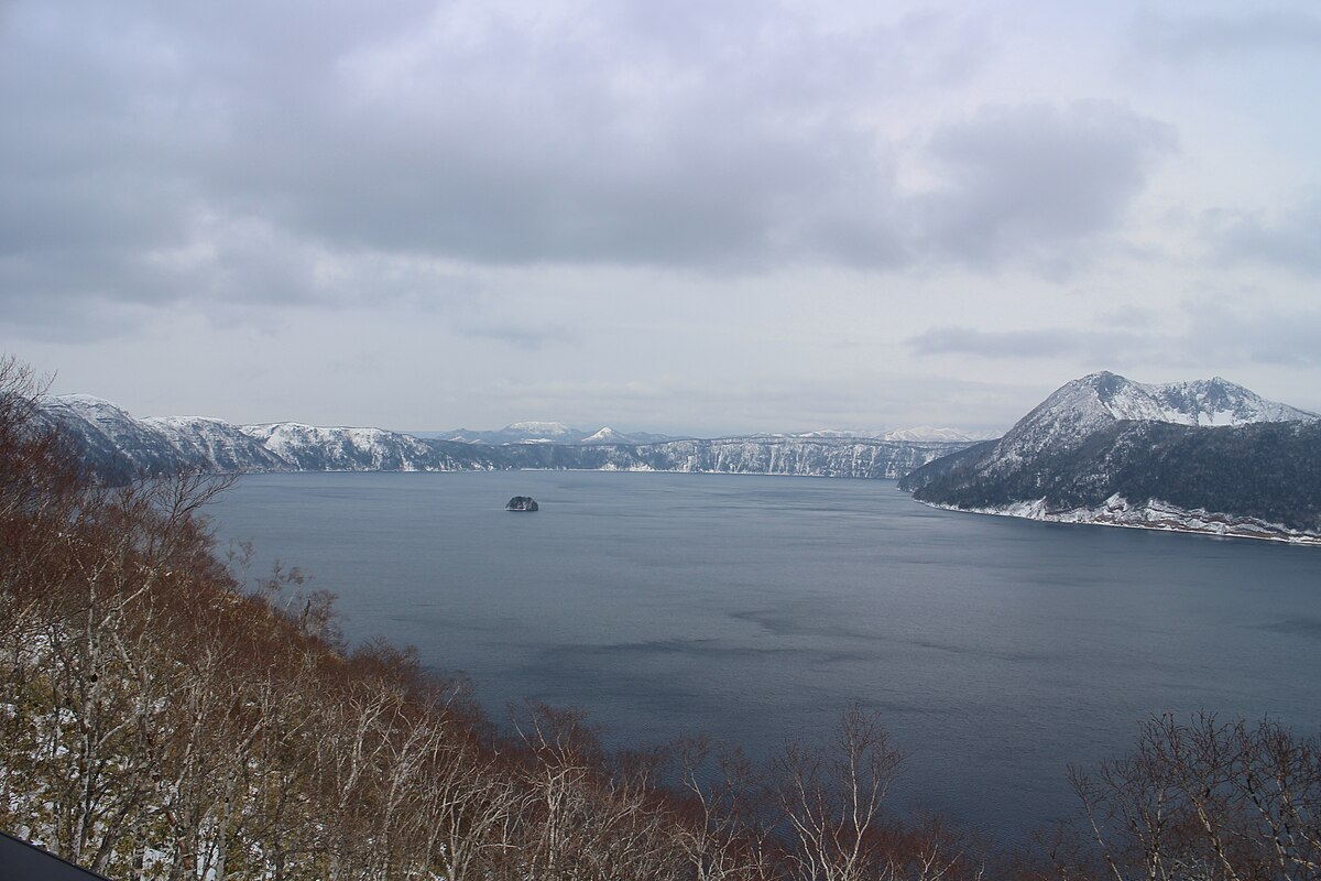 Lake Mashu in winter with snow-covered caldera rim and frozen landscape