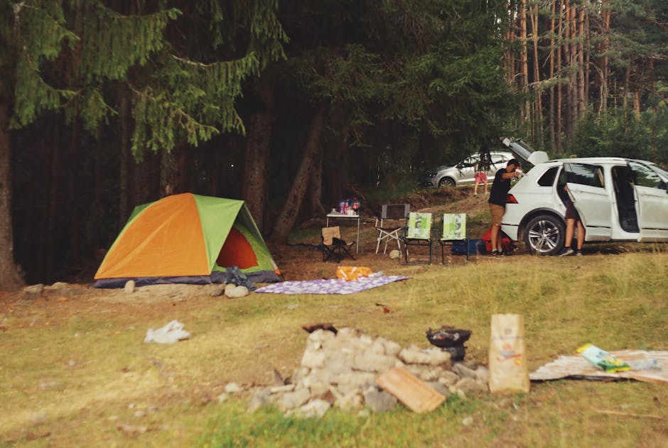 Tent and car at a peaceful forest campsite with tall trees