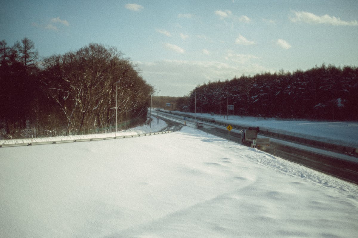 Snowy highway through forest in Hokkaido Japan during winter