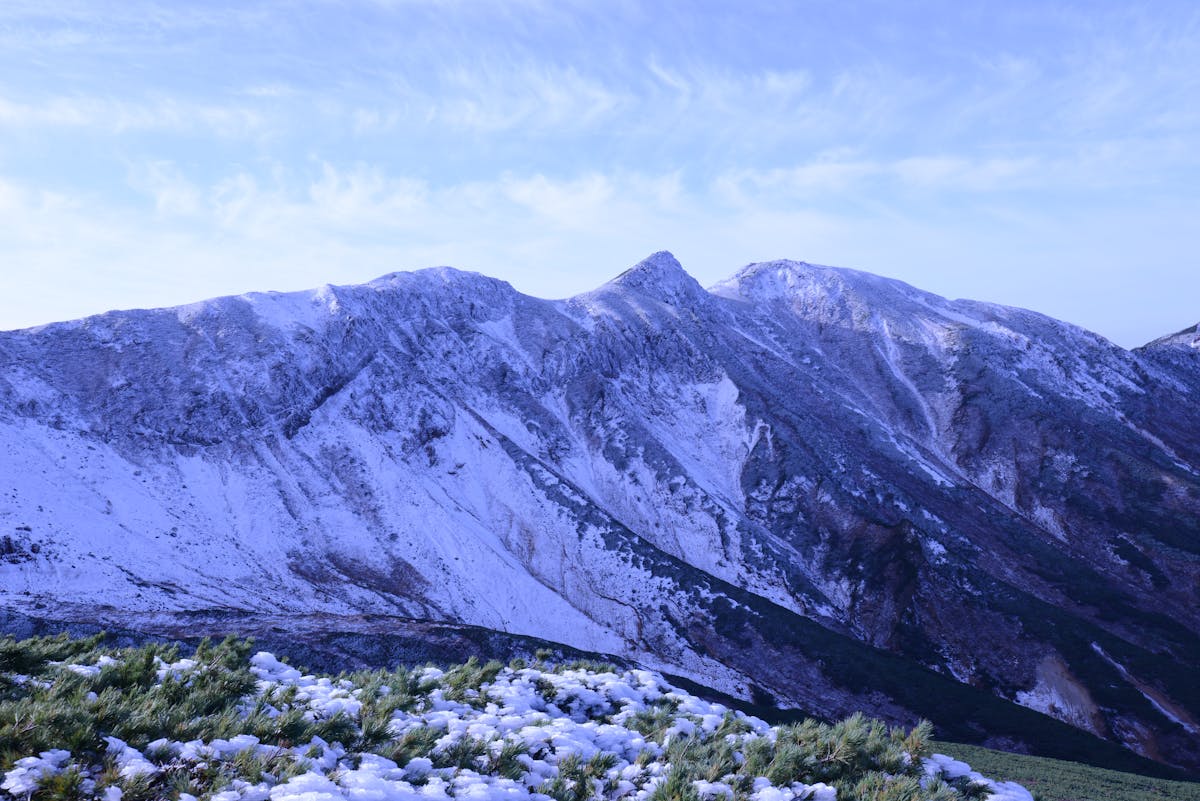 Snowcapped mountains in Hokkaido Japan with grass and shrubs in the foreground