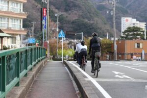 Group of cyclists on a scenic road in Japan with mountains in the background
