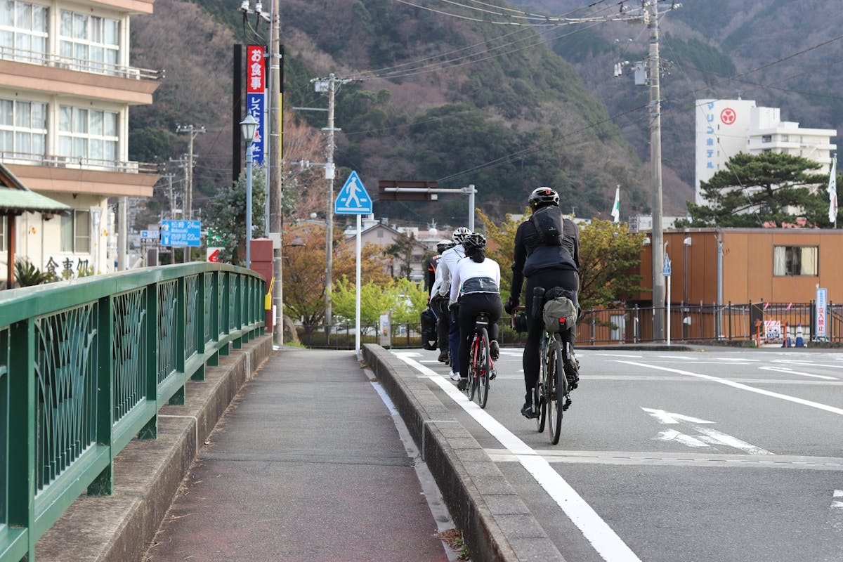 Group of cyclists on a scenic road in Japan with mountains in the background