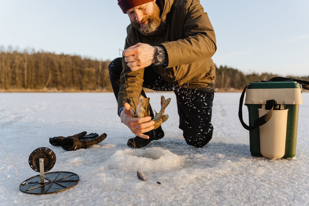 Man ice fishing on a frozen lake through a hole in the ice