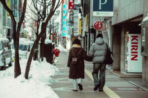 Couple walking hand in hand on a snowy sidewalk in Hokkaido Japan
