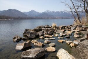Tranquil lakeside scene with boulders and mountains in Teshikaga Hokkaido