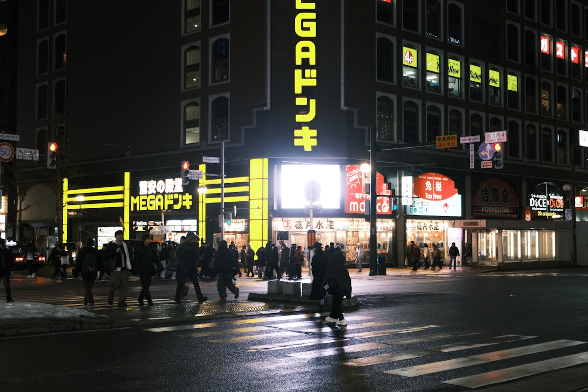 Nighttime street in Sapporo, Hokkaido with illuminated storefronts and pedestrians