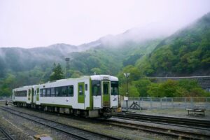 Train on tracks in Japan with misty green mountains in the background