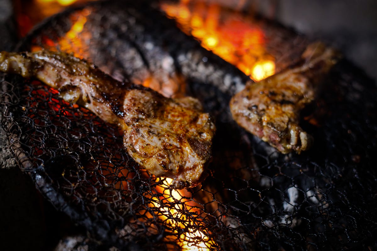 Grilled meat sizzling on an open flame BBQ grill