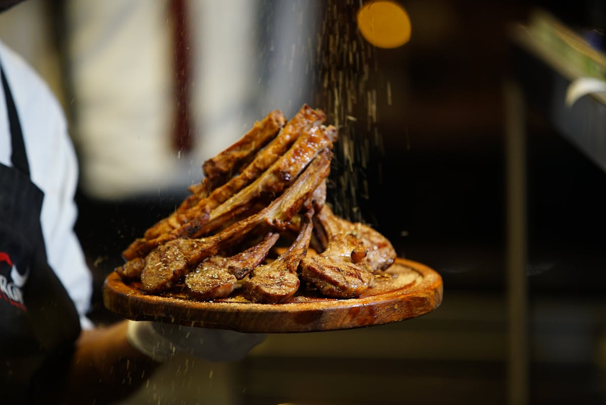 Grilled lamb chops seasoned with herbs on wooden platter