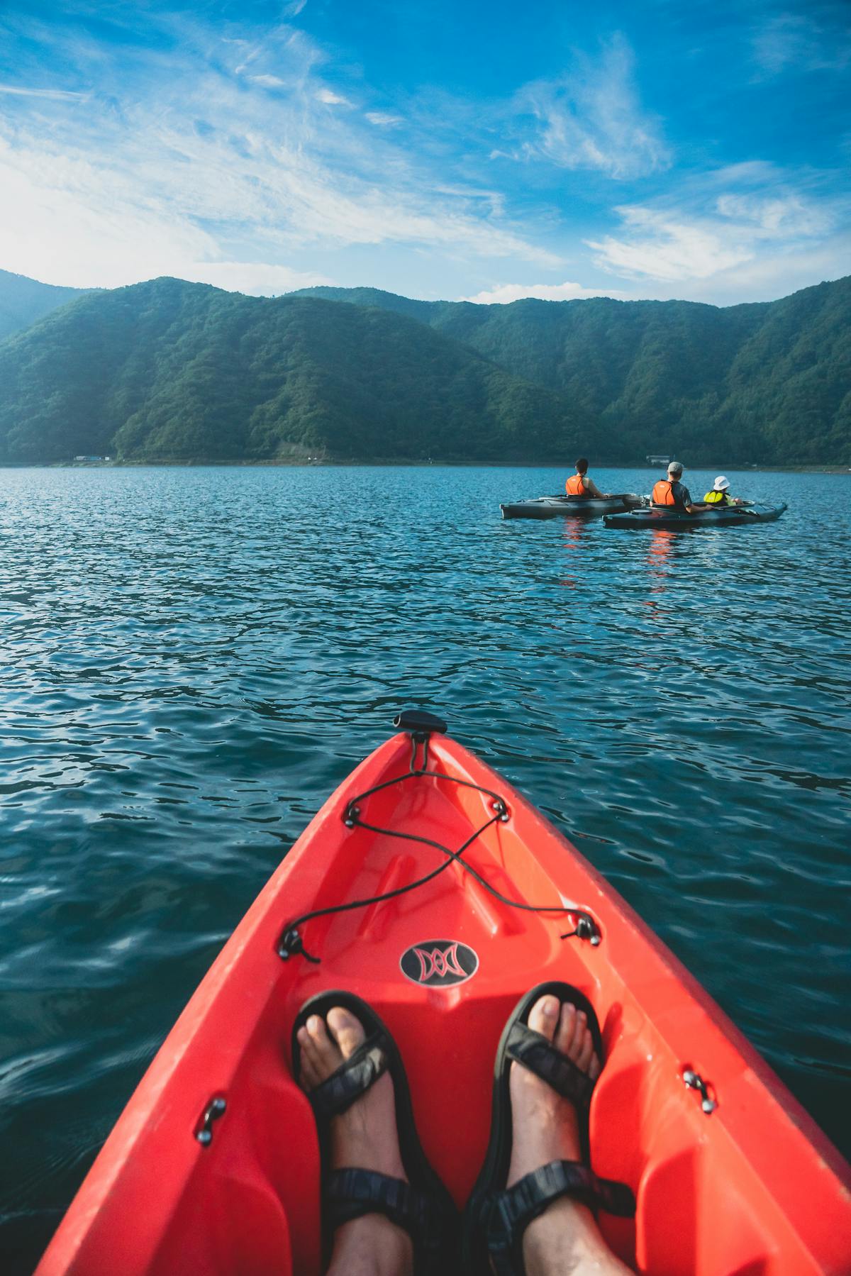 Person kayaking on a calm lake surrounded by mountains in Japan