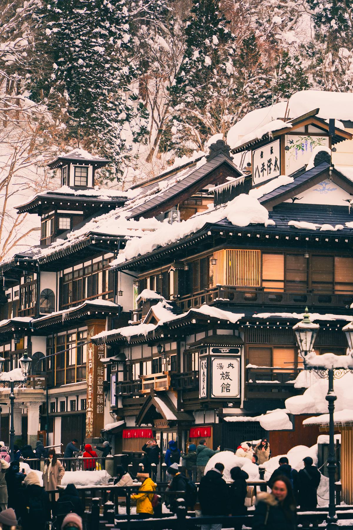 Traditional Japanese outdoor onsen hot spring bath surrounded by snow-covered trees