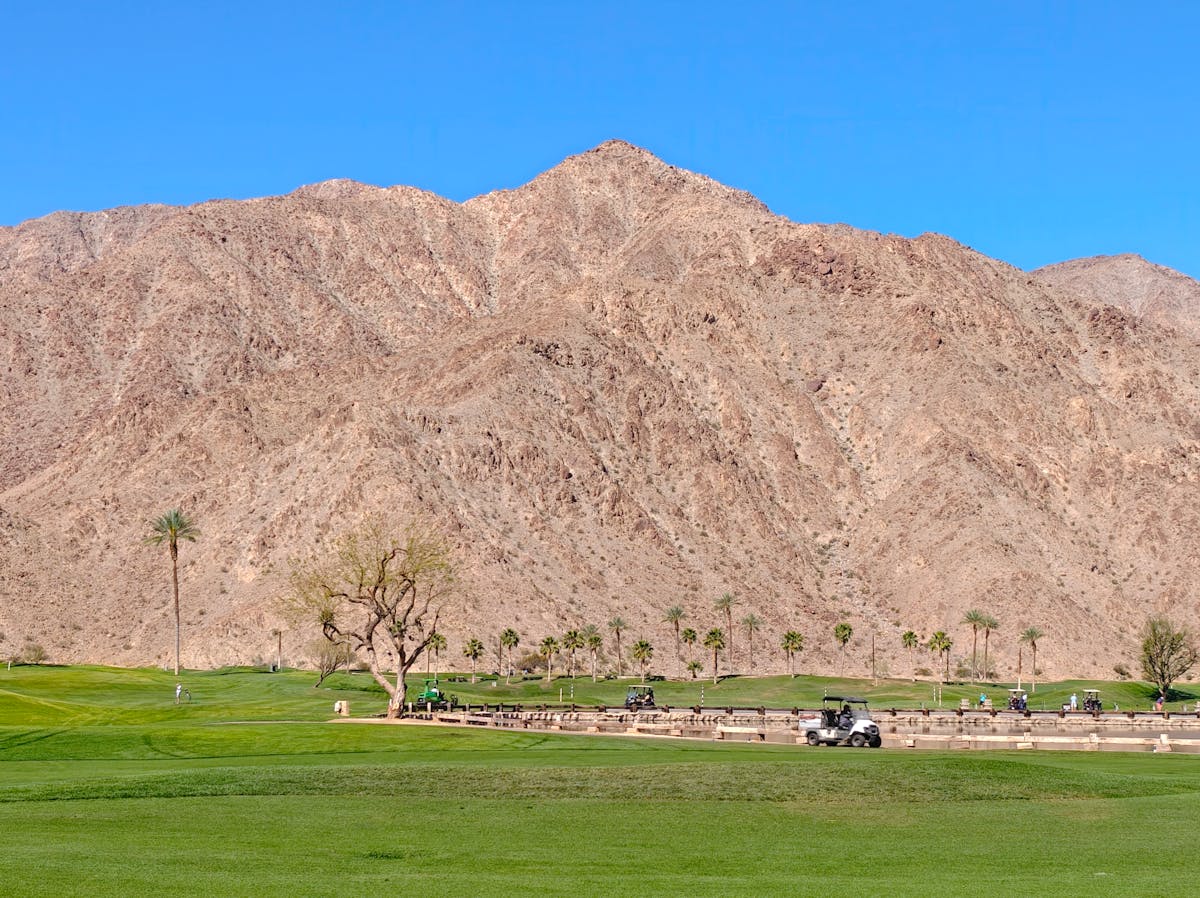 A golf course with mountains in the background under a clear blue sky