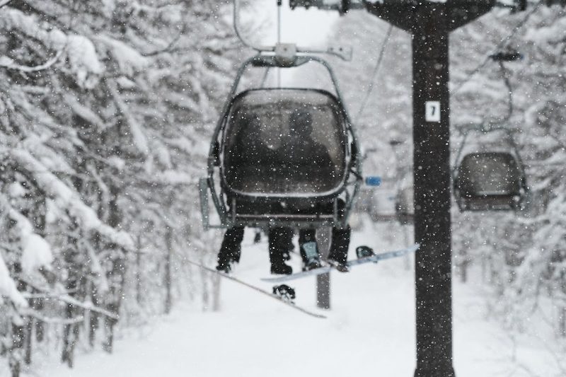Skiers on a chairlift through snow-laden forest in Niseko Japan