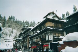 Traditional Japanese architecture in a snowy onsen town with mountains