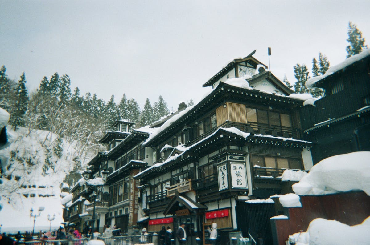 Traditional Japanese architecture in a snowy onsen town with snow-covered trees
