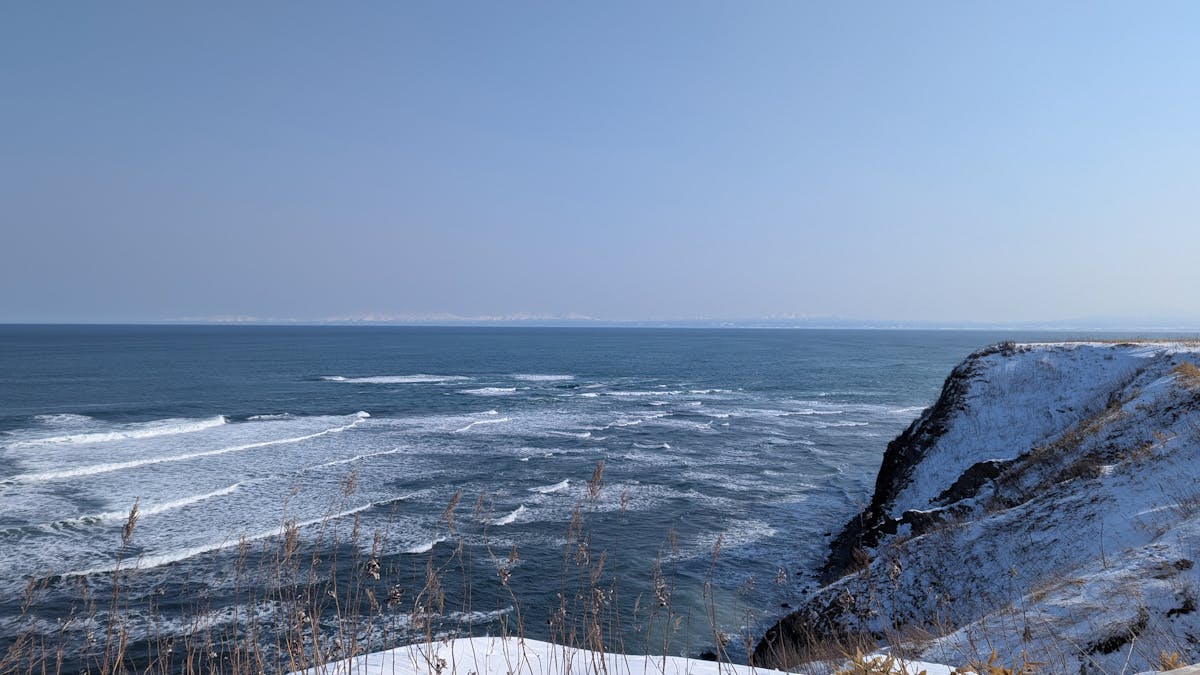 Winter coastline at Cape Shiretoko with snow-covered cliffs and blue ocean