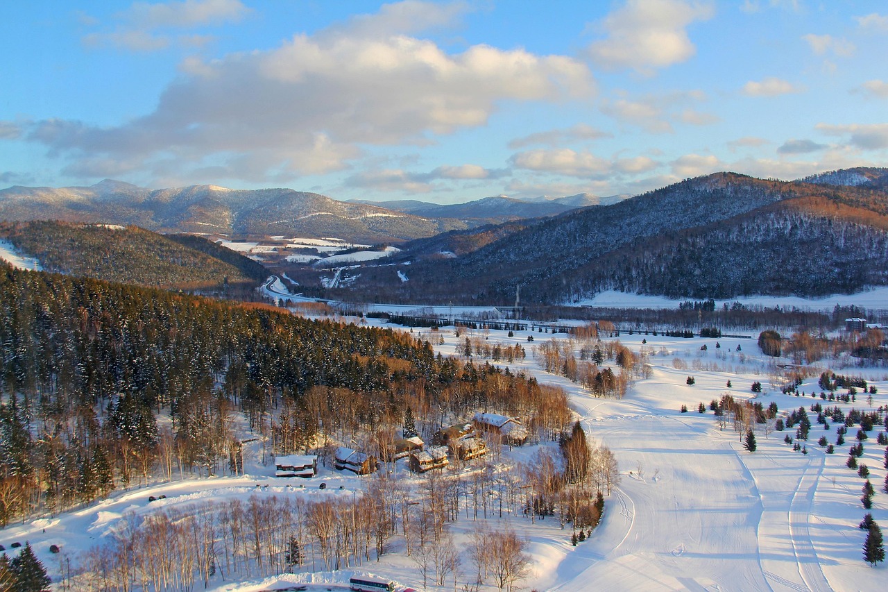 Panoramic winter view from Hoshino Resorts Tomamu showing snow-covered mountains under blue sky